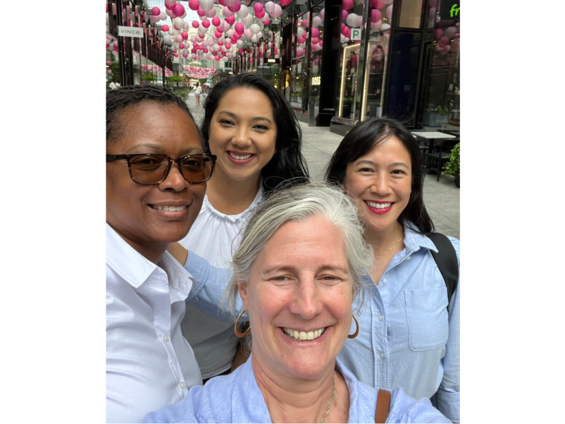 A diverse group of women colleagues happily posing for a selfie at City Center, DC.